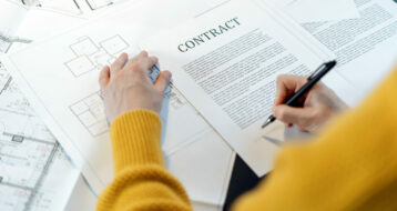 High angle view of woman reading contract, sitting behind table with project plan, analyzing real estate market, mortgage loan with low rate and signing agreement for buying property